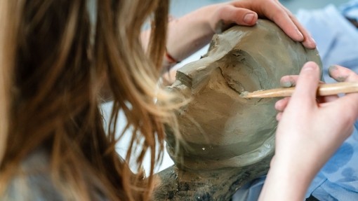 Close up of student making a clay sculpture of a face.