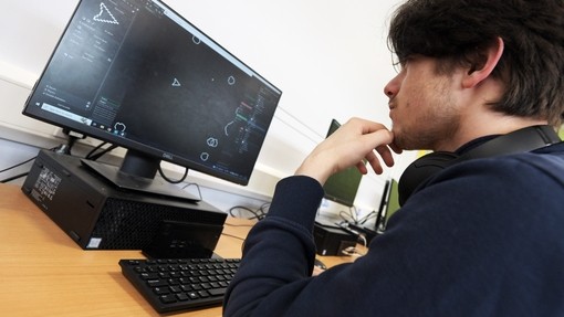 A student looking thoughtfully at a computer screen with their hand on their chin.
