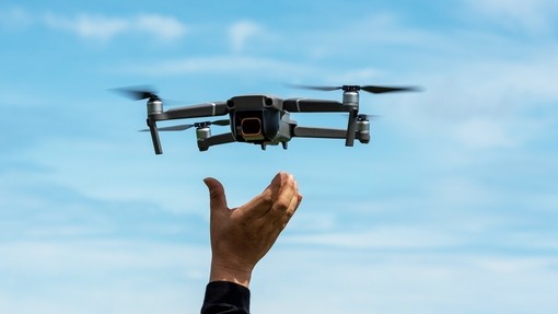 A drone landing in the hand of a pilot, with a blue sky in the background