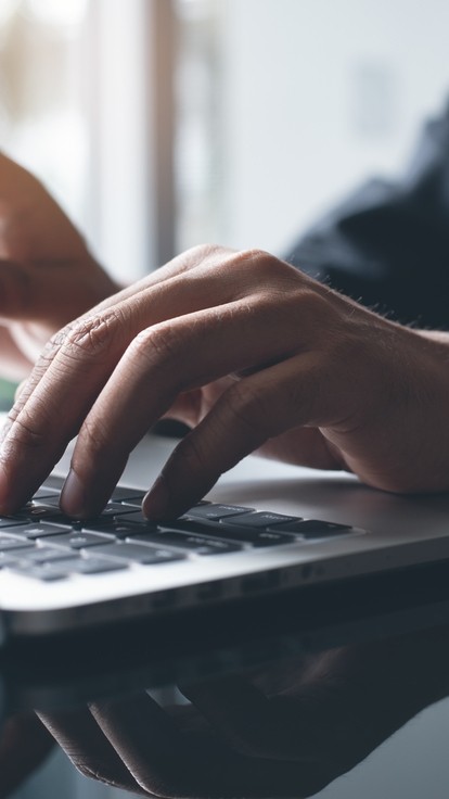 Hands of an unseen person using a laptop