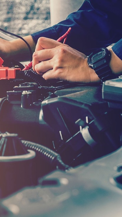 Hands of an unseen person working on the engine of a car