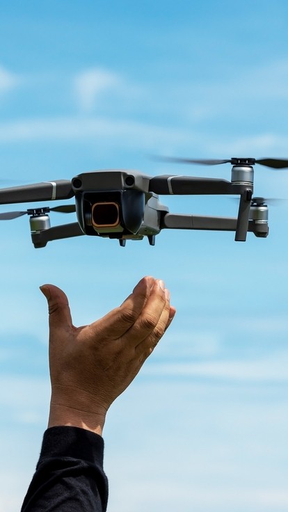 A drone landing in the hand of a pilot, with a blue sky in the background