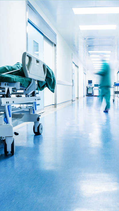 A hospital corridor with a bed nearby by the wall