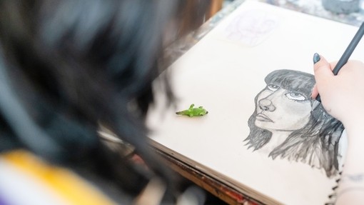 Close up of a student doing a pencil sketch portrait.