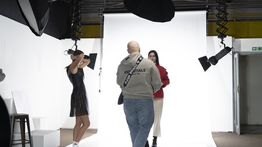 Students in a white photography studio, doing a fashion photoshoot.