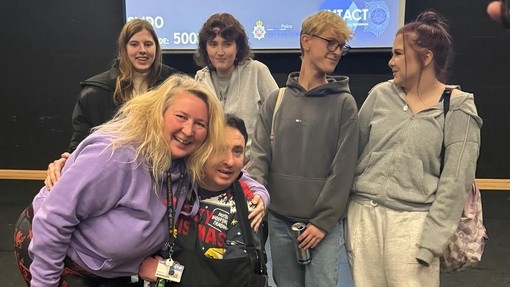 Paul in the college theatre with students being hugged by a social care lecturer