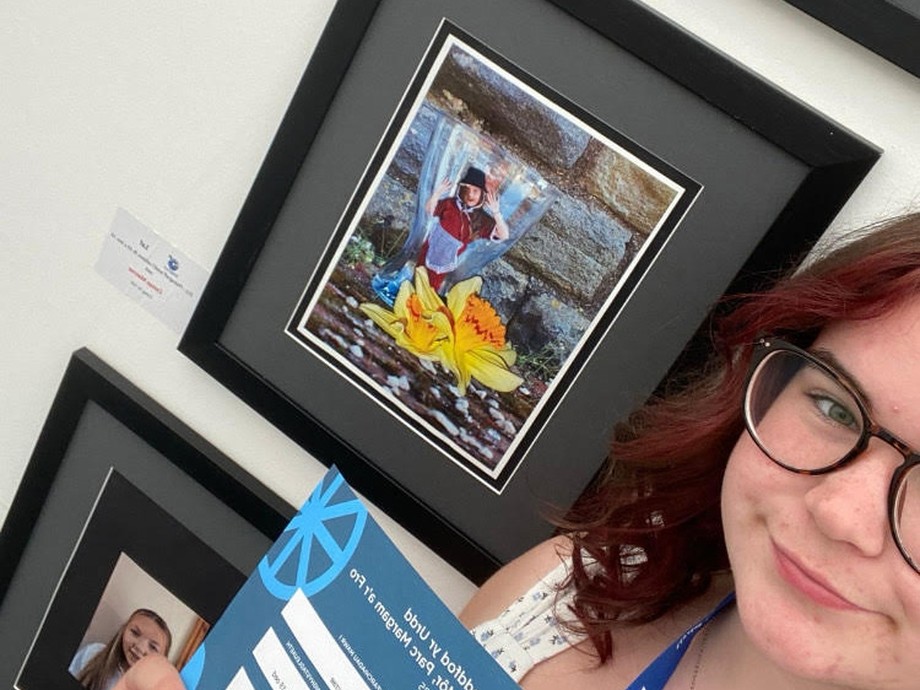 Ceirian - a selfie with her holding her score and with her imagery behind her (including traditional Welsh costume)