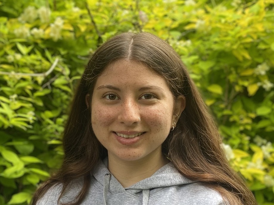 Hannah in front of some greenery wearing a Princeton hoodie