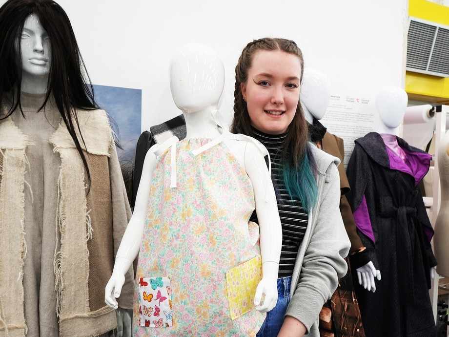 One of the students with her final garment on a child mannequin