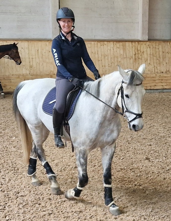 A woman on a white horse in an arena