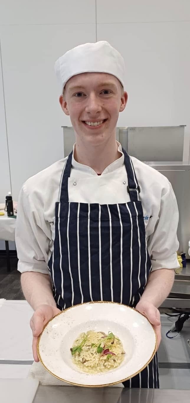 Harry holding his risotto in a chef uniform