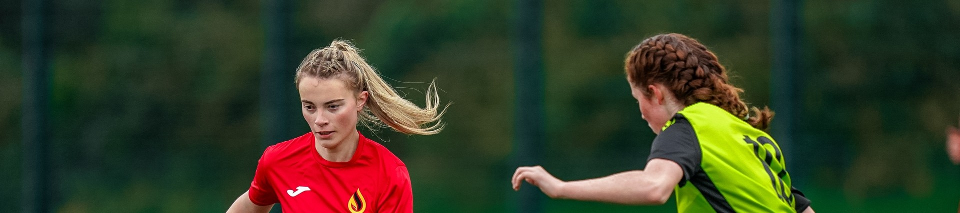 Two female student athletes playing football.