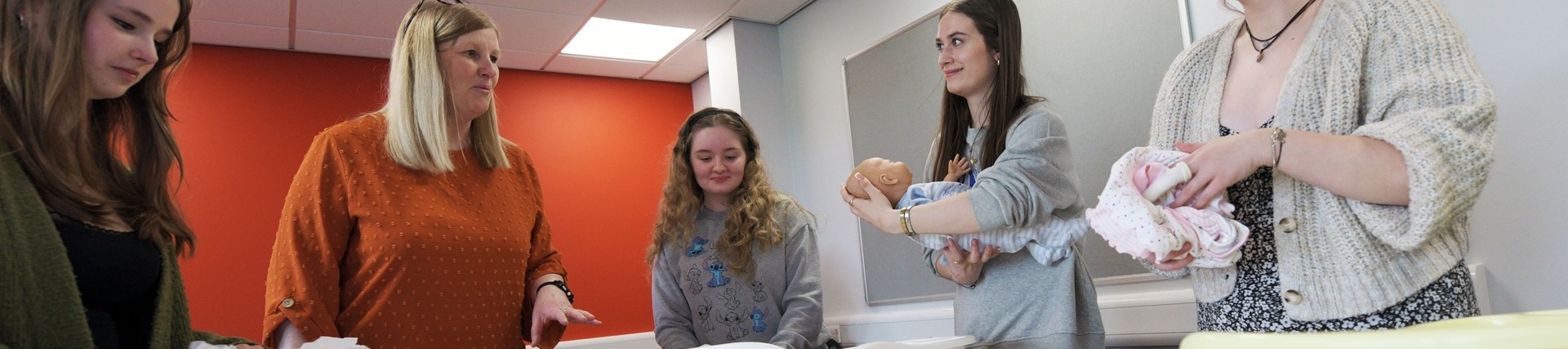 Students practicing childcare with dolls. 