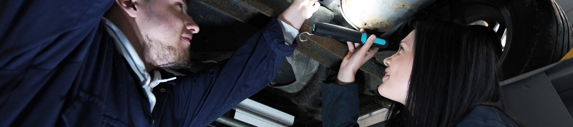 Two students working on a car.