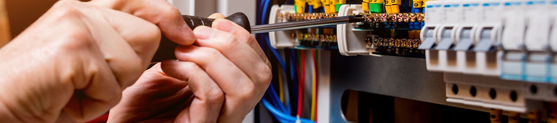 Hands of unseen person using a screwdriver on a fuse box