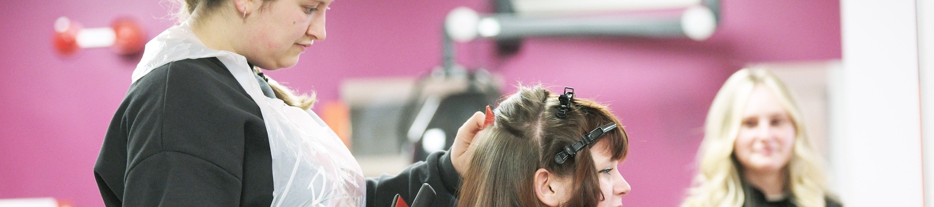 A student straightens a clients hair.