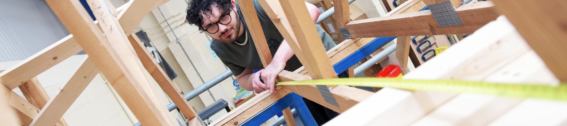 A student measuring a wooden frame.