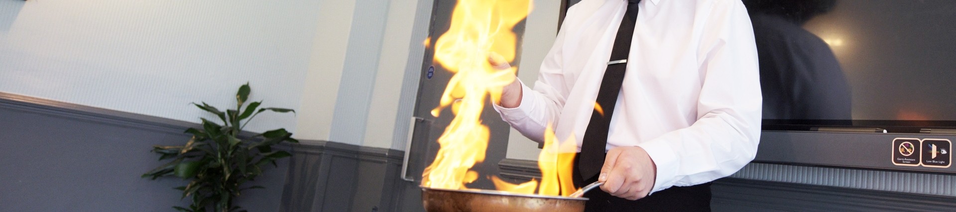 Flames erupt from a frying pan whilst a student cooks.