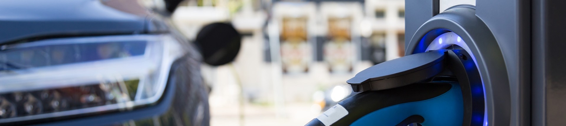 Close-up of the electric vehicle charging point, the car charging is visible to the left