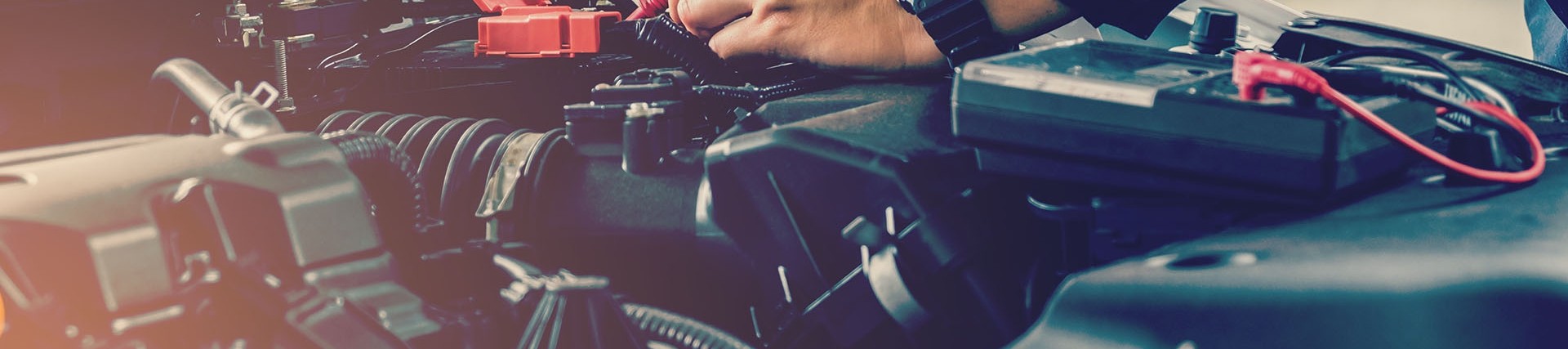 Hands of an unseen person working on the engine of a car