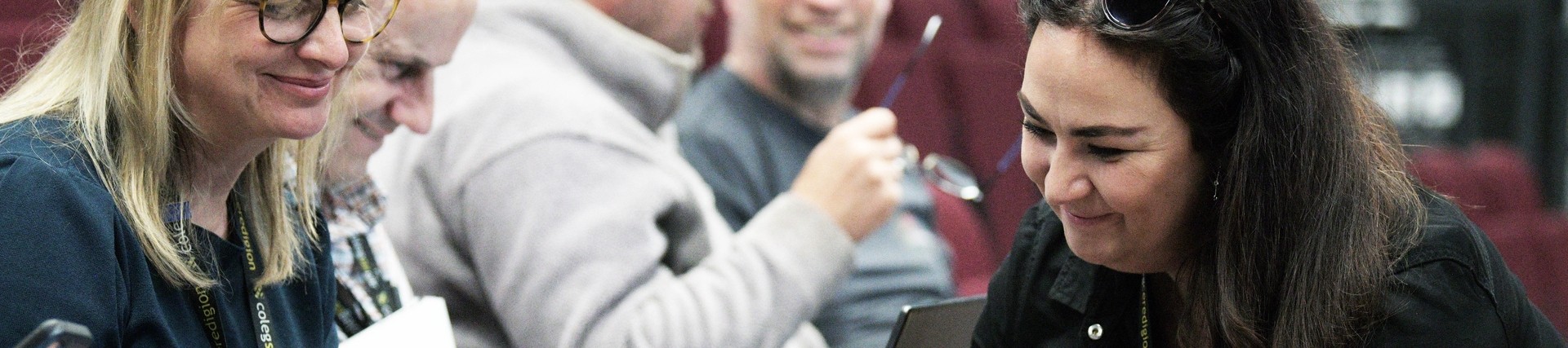 Group of adults looking at a laptop in a lecture theatre