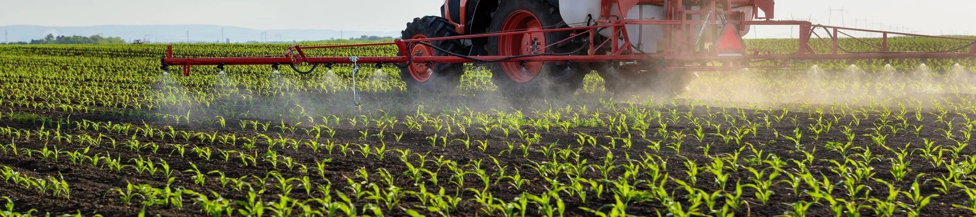 Tractor spreading pesticides on a crop field