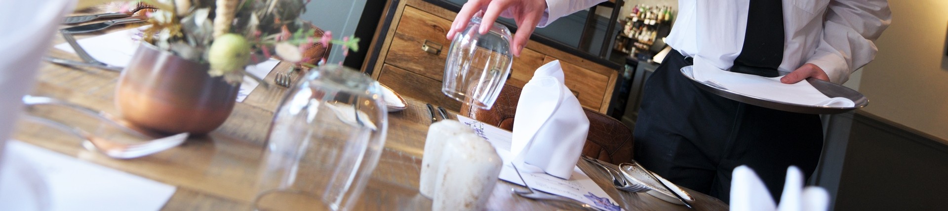 Student laying a table in a training restaurant