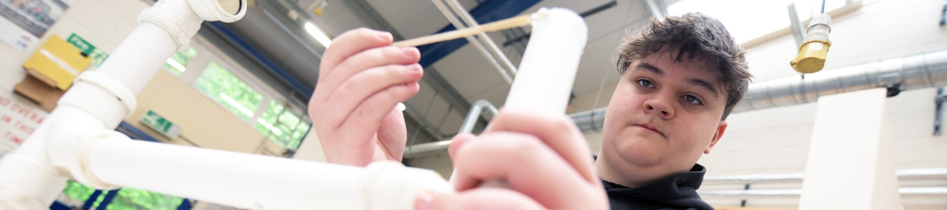 Plumbing student practicing with white plastic pipes