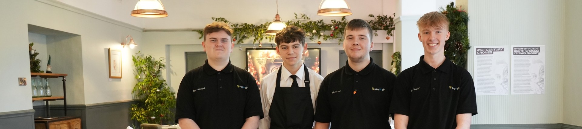 Four catering and hospitality students standing in a training restaurant