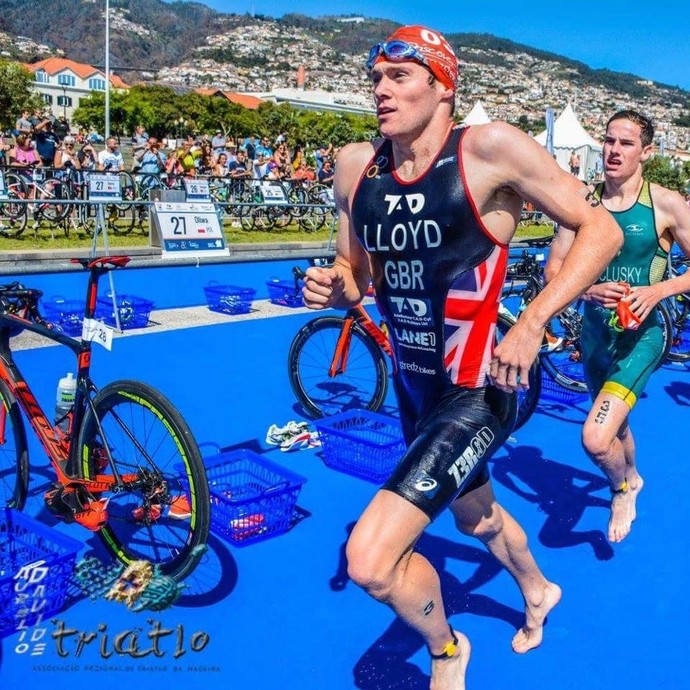 Student athlete in a Team GB sports kit and red swimming cap, racing in a triathlon.