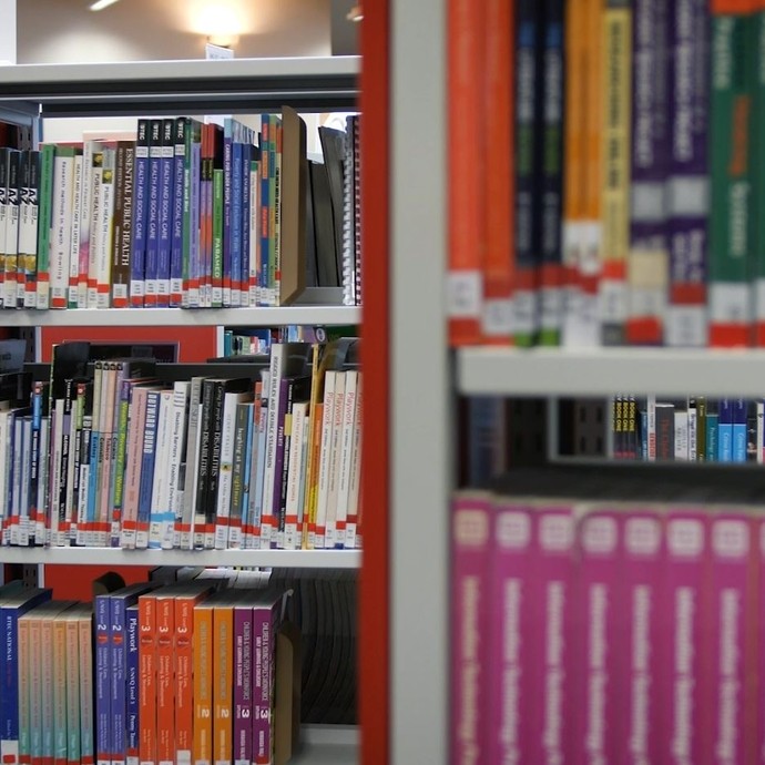 Close up on some library shelves full of books.