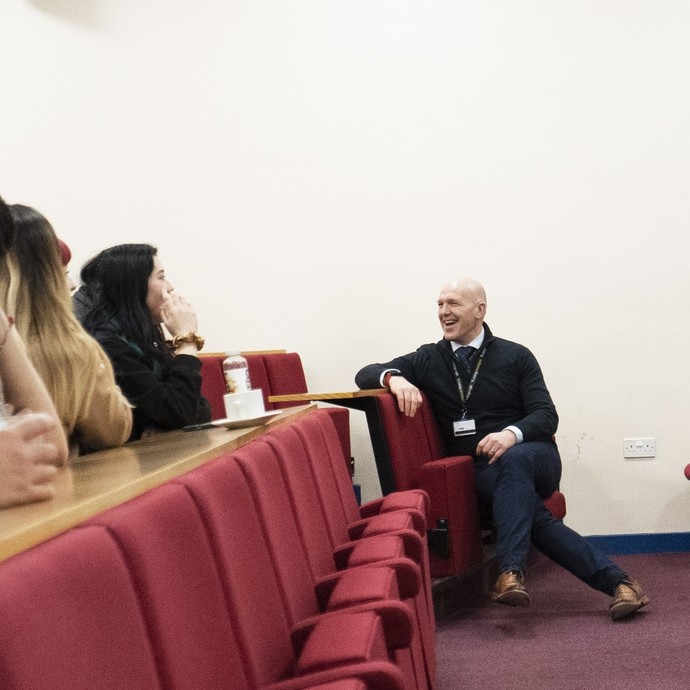 Two lecturers speaking to students in the front row of the lecture theatre