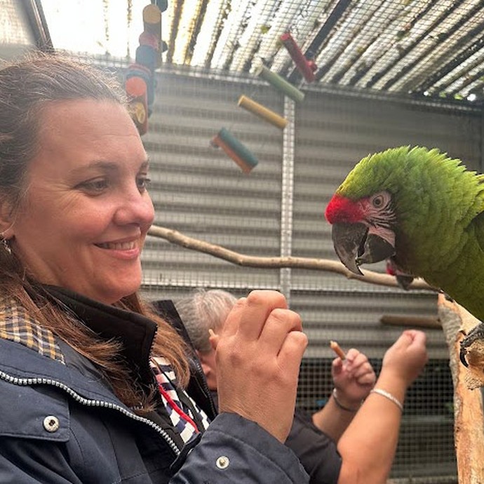 Emma (lecturer) up close to an exotic green and red bird