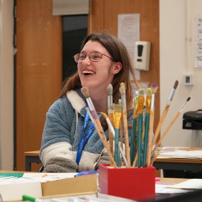 A student smiling and working at a desk